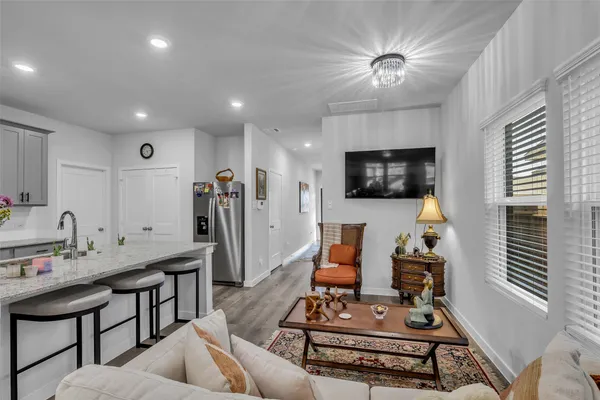 a living room with furniture a flat screen tv and kitchen view