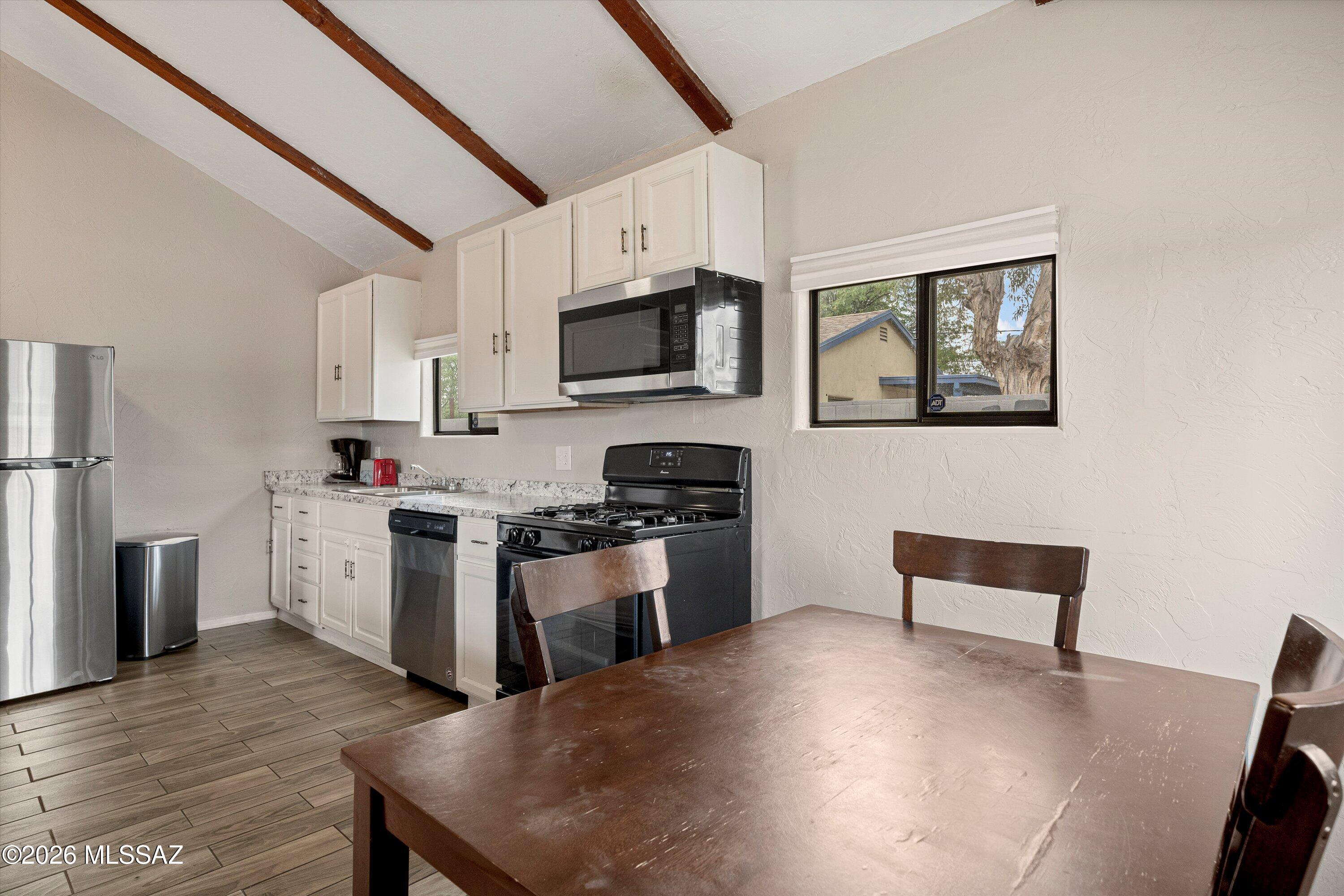 2841 North Richey Boulevard Tucson, AZ 85716 - Photo 11 of 30 a kitchen with stainless steel appliances granite countertop a stove a sink a microwave a refrigerator a microwave oven with white cabinets and wooden floor