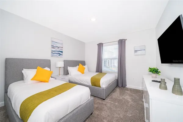 a bedroom with two beds and a flat screen tv