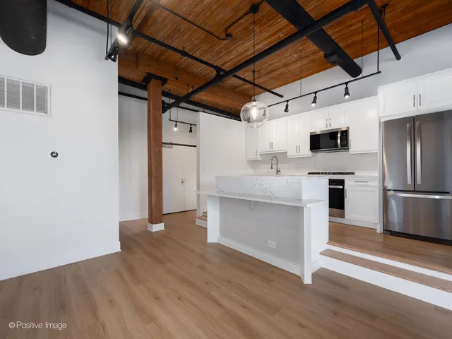 a kitchen with stainless steel appliances wooden floor sink and refrigerator