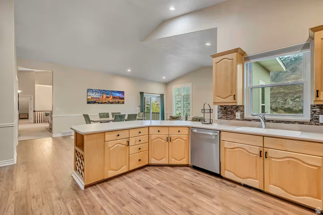11789 Nicklaus Road Sandy, UT 84092 - Photo 8 of 58 Kitchen with a peninsula, light wood finish cabinetry, decorative backsplash, light countertops, and dishwasher