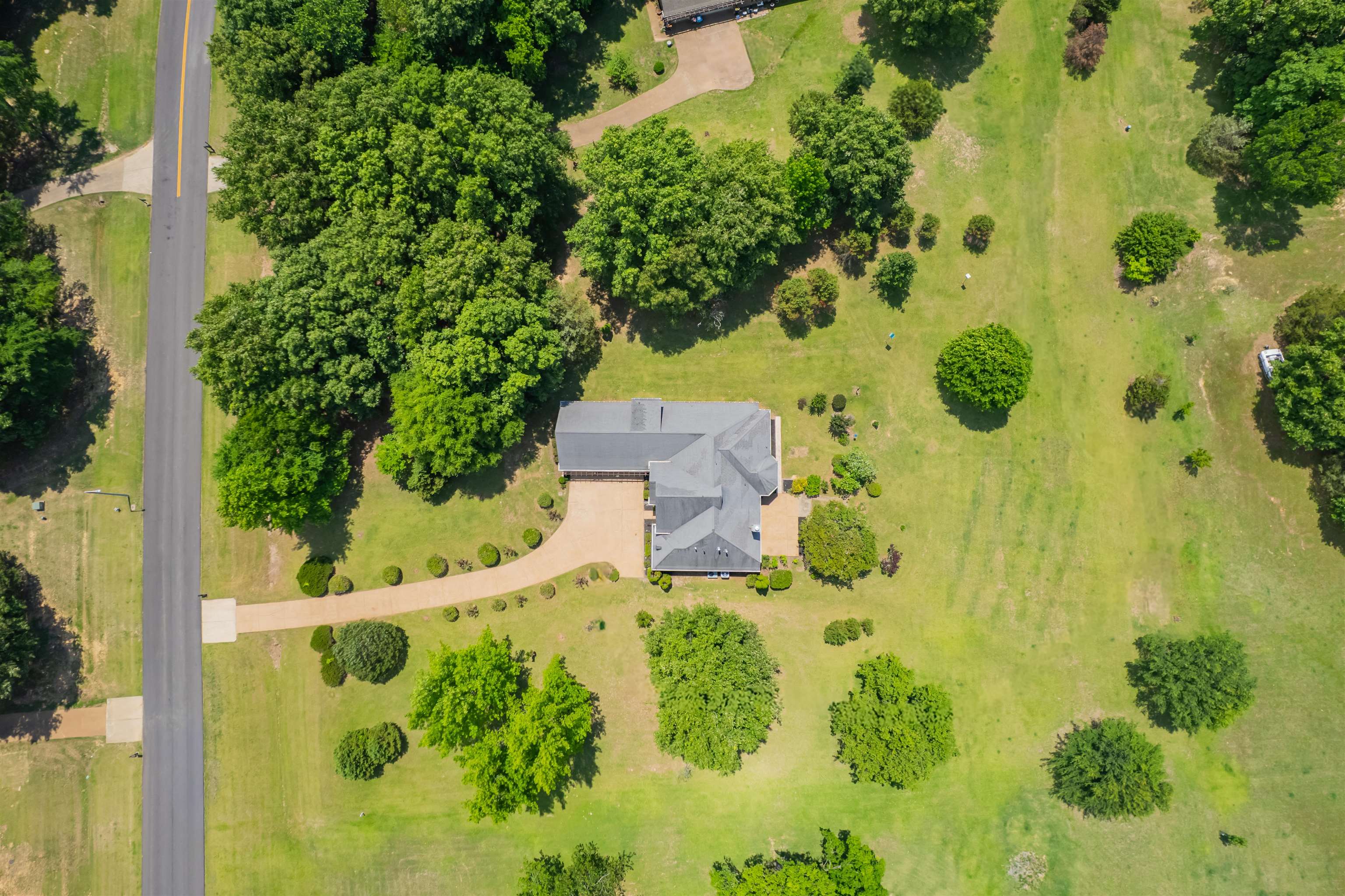 5035 Brian Ridge Road Arlington, TN 38002 - Photo 4 of 40 Expansive property featuring a single-story residence with a gray shingle roof, a curving paved driveway, mature trees, and a substantial grassy lawn