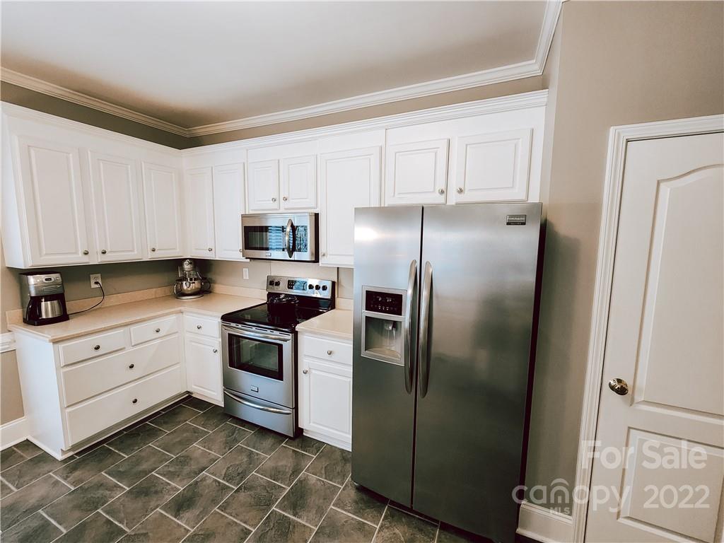 8408 Forest Shadow Circle Cornelius, NC 28031 - Photo 4 of 24 a kitchen with white cabinets and stainless steel appliances