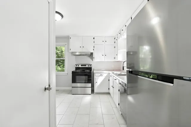 a kitchen with a refrigerator and white cabinets