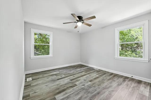 a view of an empty room with wooden floor and a window