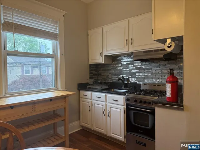 a kitchen with stainless steel appliances granite countertop a stove and a white cabinets
