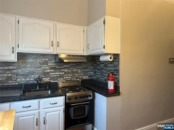 a kitchen with stainless steel appliances granite countertop a stove a sink and white cabinets