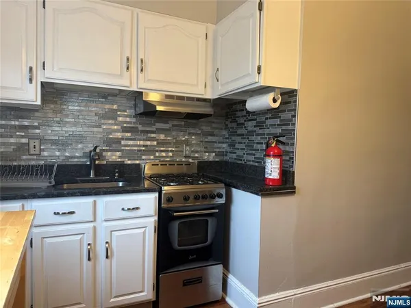 a kitchen with stainless steel appliances granite countertop a stove a sink and white cabinets