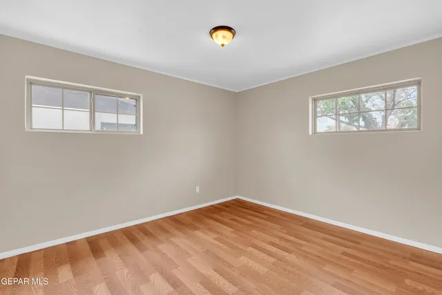 a view of an empty room with window and wooden floor