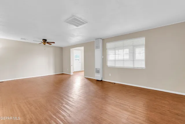 an empty room with wooden floor cabinet and windows