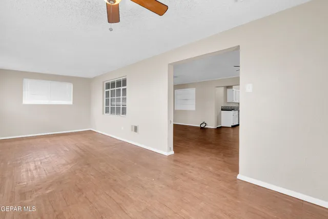 an empty room with ceiling fan and window