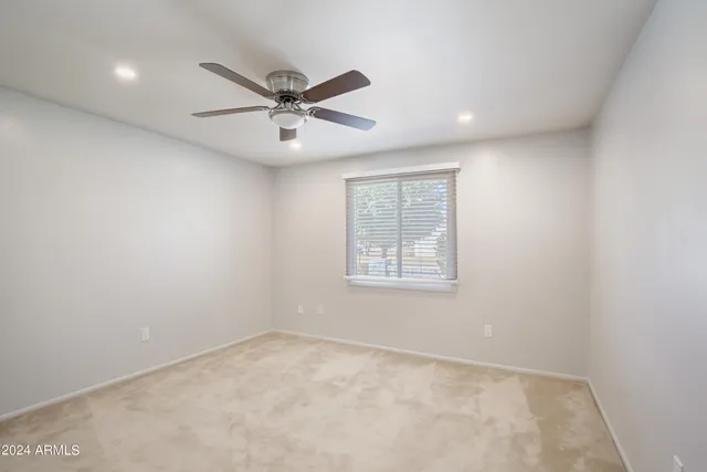 an empty room with a window and ceiling fan