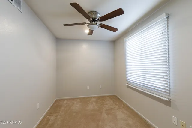 an empty room with a window and a fan