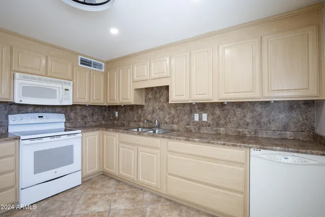a kitchen with granite countertop white cabinets and white appliances