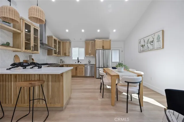 a kitchen with stainless steel appliances granite countertop a table chairs sink and cabinets