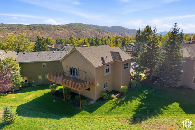 7396 Brook Hollow Loop Road Park City, UT 84098 - Photo 39 of 60 Expansive rear yard with manicured lawn, multi-level dwelling with a neutral-toned exterior, elevated deck with light wood railing, and surrounding mature trees