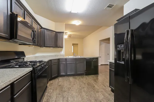 a kitchen with stainless steel appliances granite countertop a stove refrigerator and cabinets