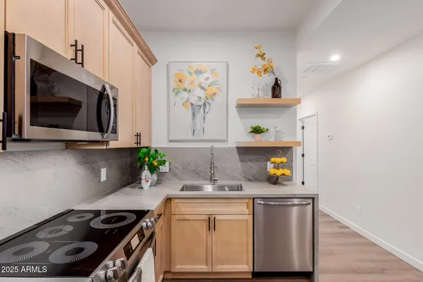a living room with stainless steel appliances furniture a flat screen tv and a refrigerator