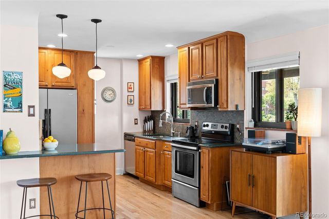 a kitchen with stainless steel appliances kitchen island granite countertop a sink a stove and a wooden floors