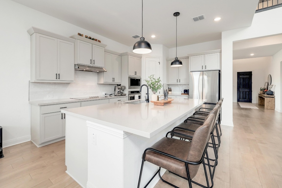 100 Garden Rose Pass Georgetown, TX 78628 - Photo 11 of 39 a kitchen with stainless steel appliances kitchen island granite countertop a sink a center island a stove and a cabinets