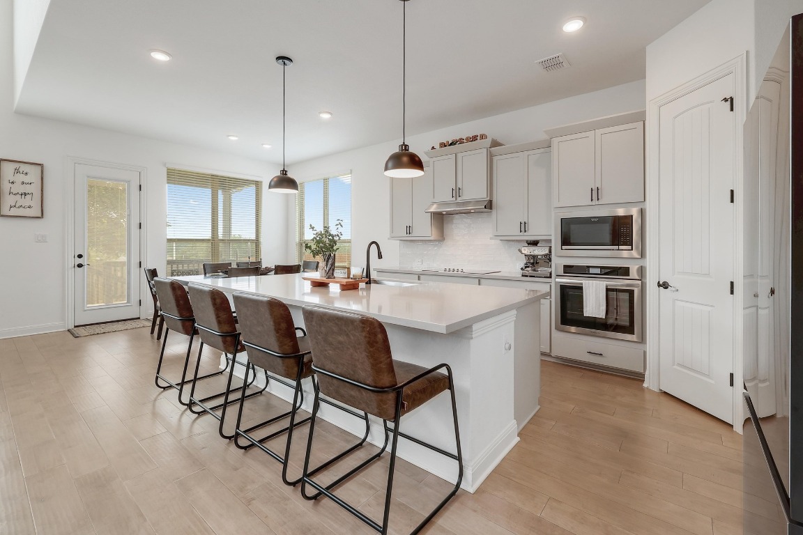 100 Garden Rose Pass Georgetown, TX 78628 - Photo 12 of 39 a kitchen with stainless steel appliances granite countertop a stove a sink a oven a dining table and chairs