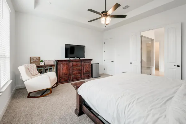 a spacious bedroom with a bed a couch and a flat screen tv