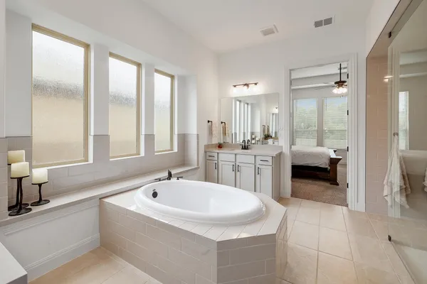 a en suite bathroom with a double vanity sink a mirror and a bathtub