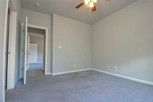 a view of an empty room and a chandelier fan