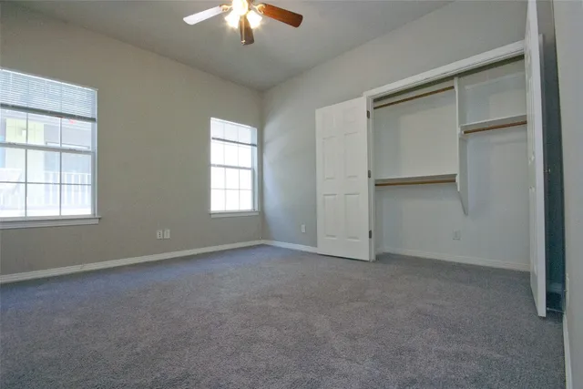 an empty room with a chandelier fan and windows