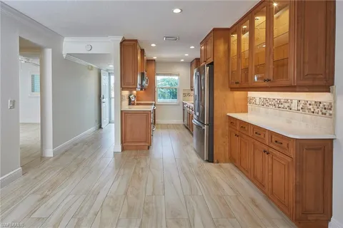 a kitchen with stainless steel appliances granite countertop a refrigerator a sink dishwasher a stove and white countertops with wooden floor