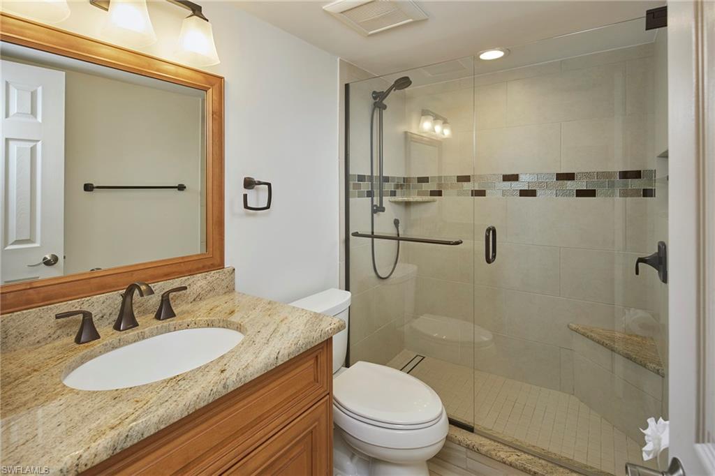 3100 Binnacle Drive, Unit 305 Naples, FL 34103 - Photo 9 of 12 a bathroom with a granite countertop sink a mirror a toilet and shower