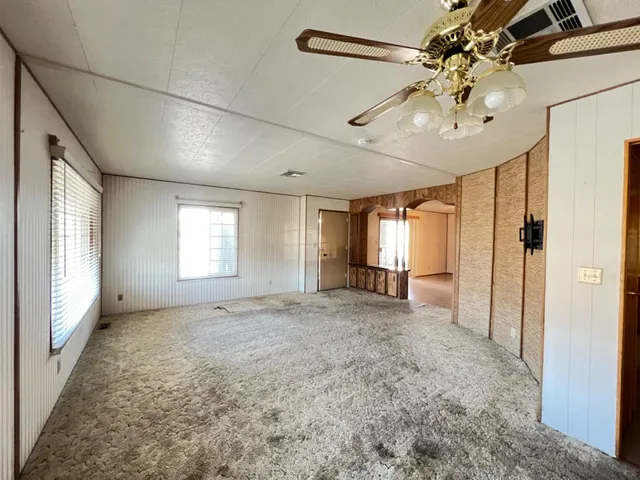 en empty room with windows and ceiling fan
