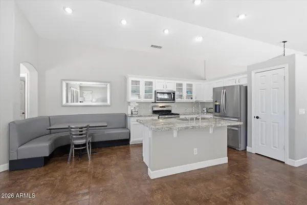 a kitchen with stainless steel appliances kitchen island granite countertop a refrigerator a stove a sink dishwasher and white cabinets with wooden floor