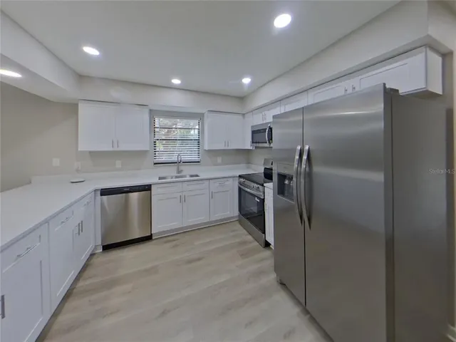 a kitchen with a refrigerator sink and cabinets