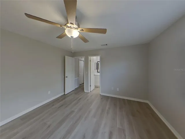 a view of a room with wooden floor and a ceiling fan