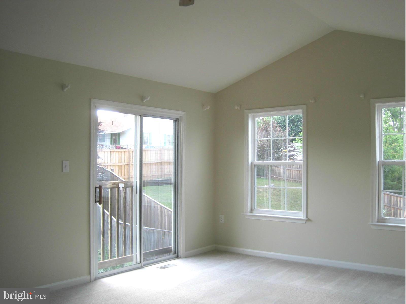 Living room with vaulted ceiling opens to backyard