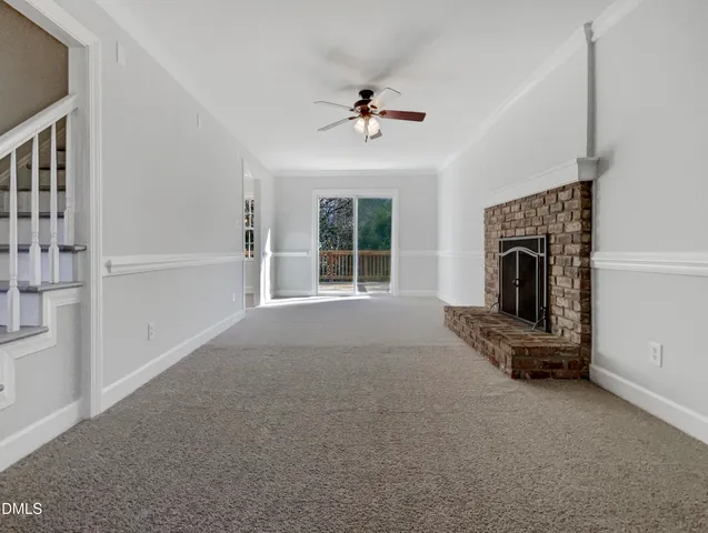 an empty room with windows fireplace and fans