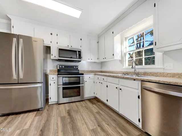 a kitchen with granite countertop a refrigerator and a stove top oven