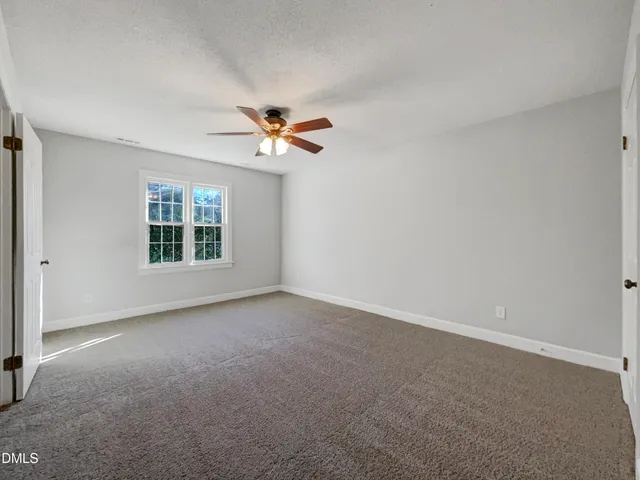 an empty room with windows and chandelier fan