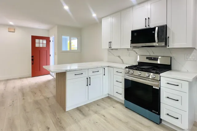 a kitchen with granite countertop white cabinets and stainless steel appliances