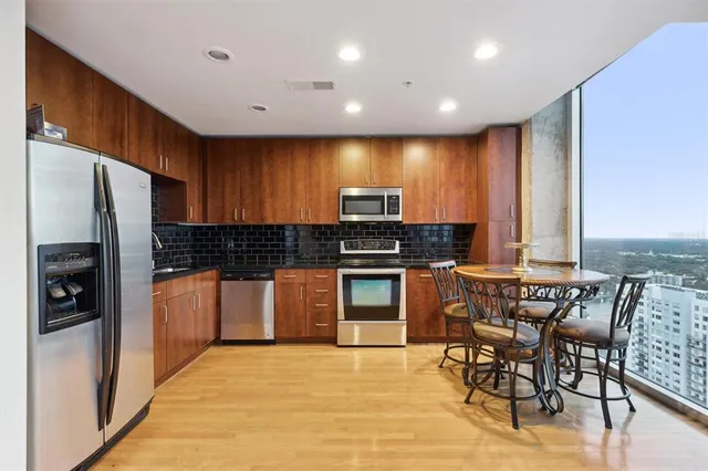 a kitchen with stainless steel appliances granite countertop a sink a stove a refrigerator cabinets and a microwave