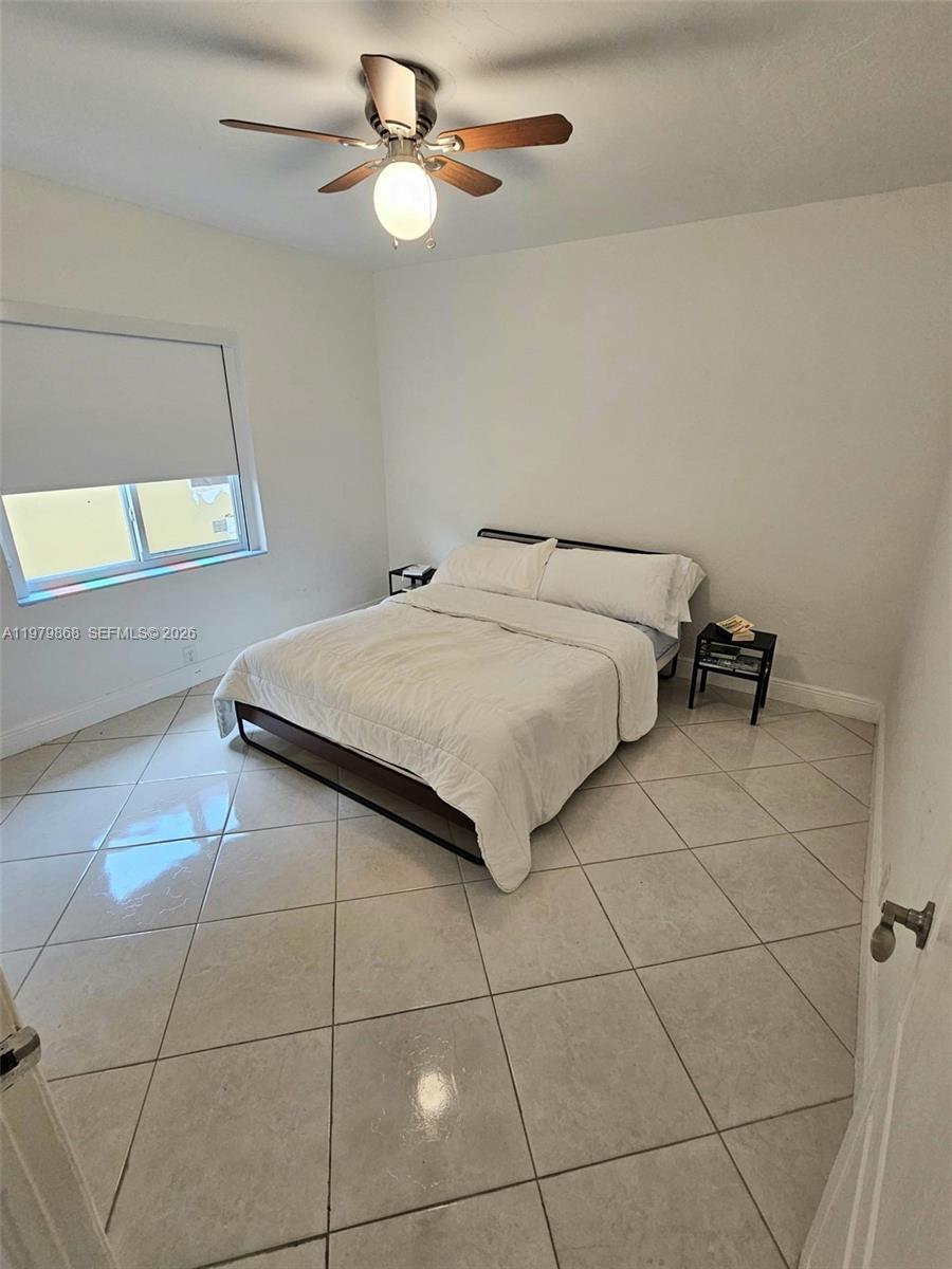 7400 Harding Avenue, Unit 22 Miami Beach, FL 33141 - Photo 14 of 26 a bedroom with a bed and a chandelier fan