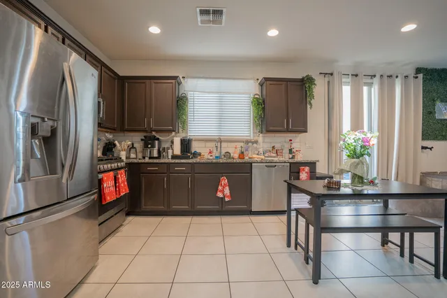 a kitchen with stainless steel appliances granite countertop a refrigerator sink and wooden cabinets