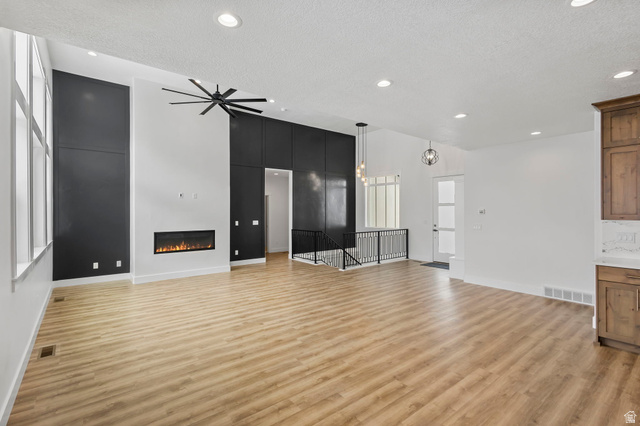 728 East Mountain Road North Ogden, UT 84414 - Photo 5 of 28 Vaulted ceiling great room featuring a linear electric fireplace, wood-finish flooring, a contemporary ceiling fan, and tall windows