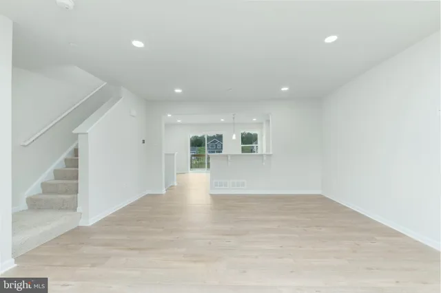 a view of an empty room with wooden floor and staircase