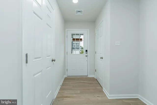 a view of a hallway with wooden floor and a bathroom
