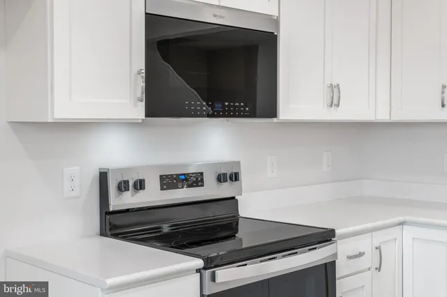 a kitchen with white cabinets and black appliances