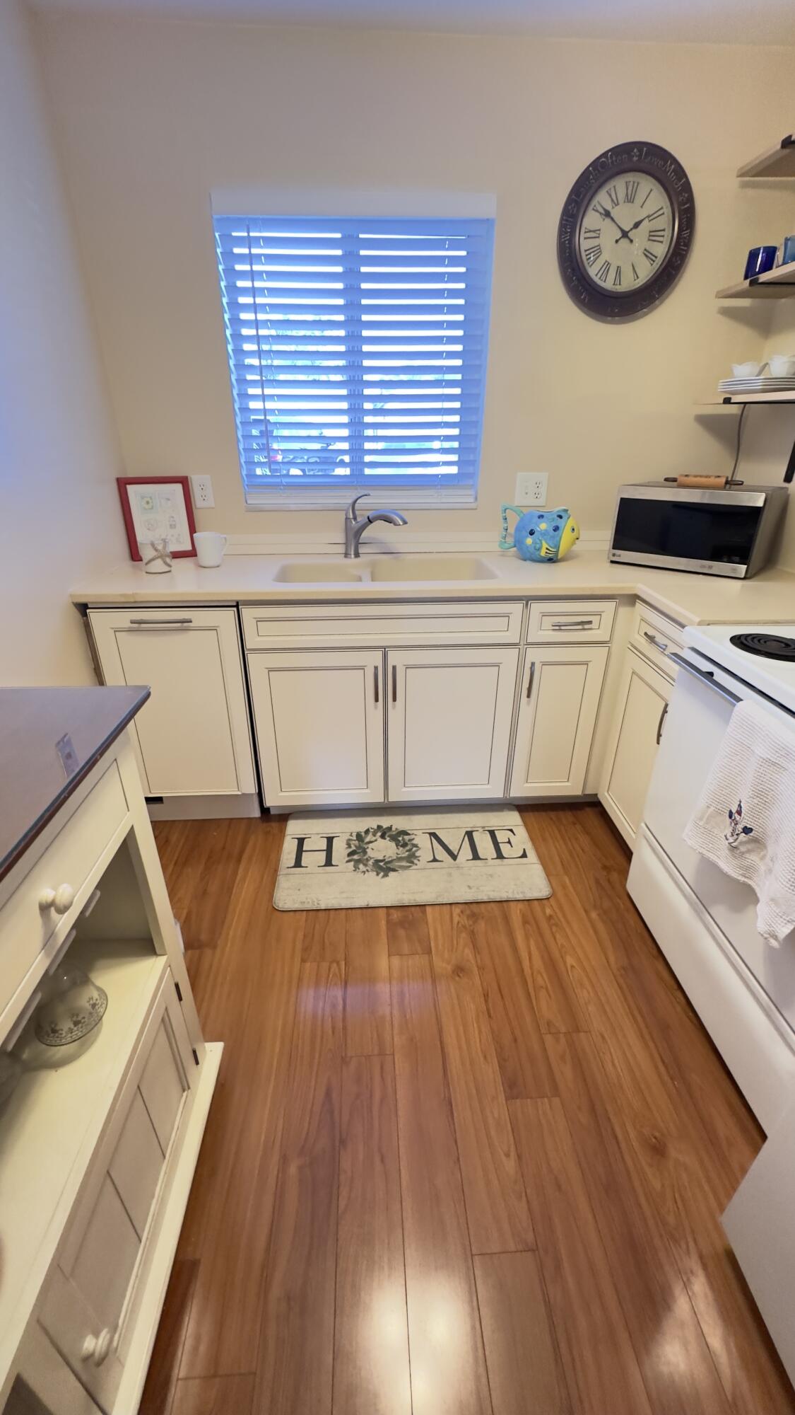 3 Garden Street, Unit 105K Tequesta, FL 33469 - Photo 7 of 41 a view of a kitchen with wooden floor and a clock on wall