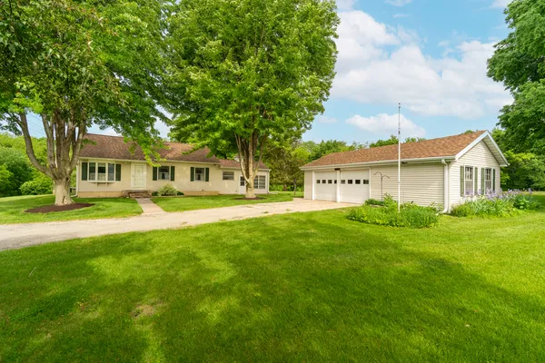 a view of a house with a big yard plants and large trees