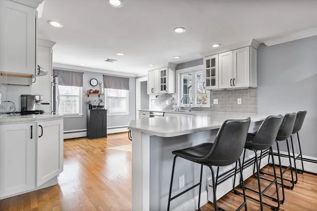 a kitchen with kitchen island granite countertop wooden floors and white cabinets